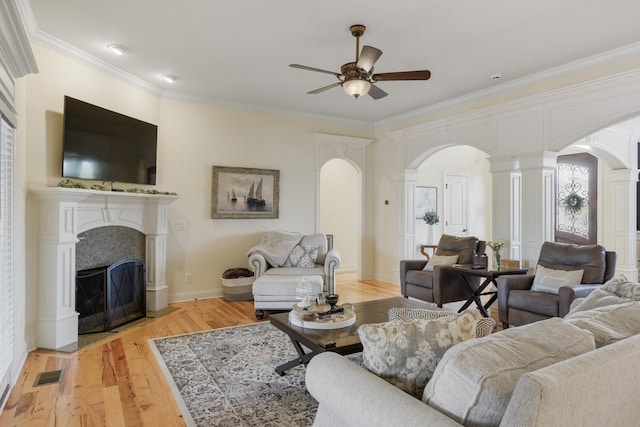 living room with crown molding, ornate columns, ceiling fan, and light wood-type flooring