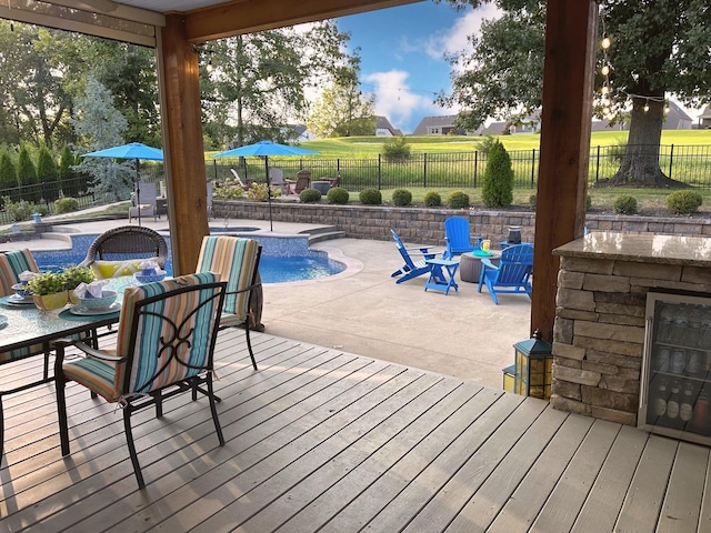 wooden terrace featuring a fenced in pool, outdoor dining area, a fenced backyard, and a bar