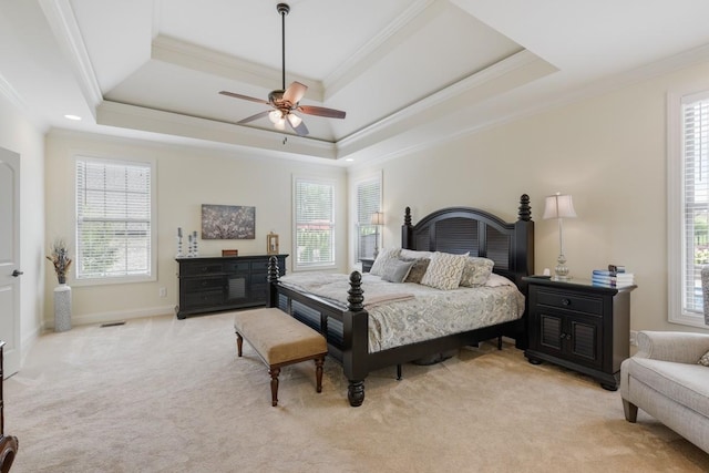 bedroom with crown molding, ceiling fan, a tray ceiling, and light colored carpet