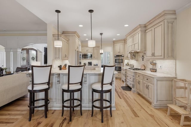 kitchen with crown molding, a breakfast bar area, hanging light fixtures, stainless steel appliances, and french doors