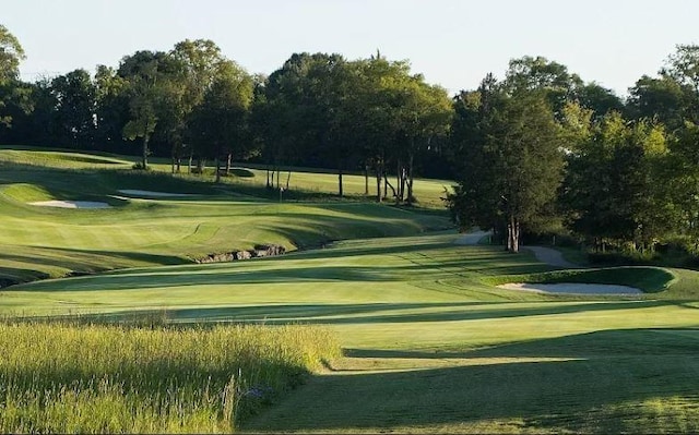 view of property's community featuring view of golf course and a yard