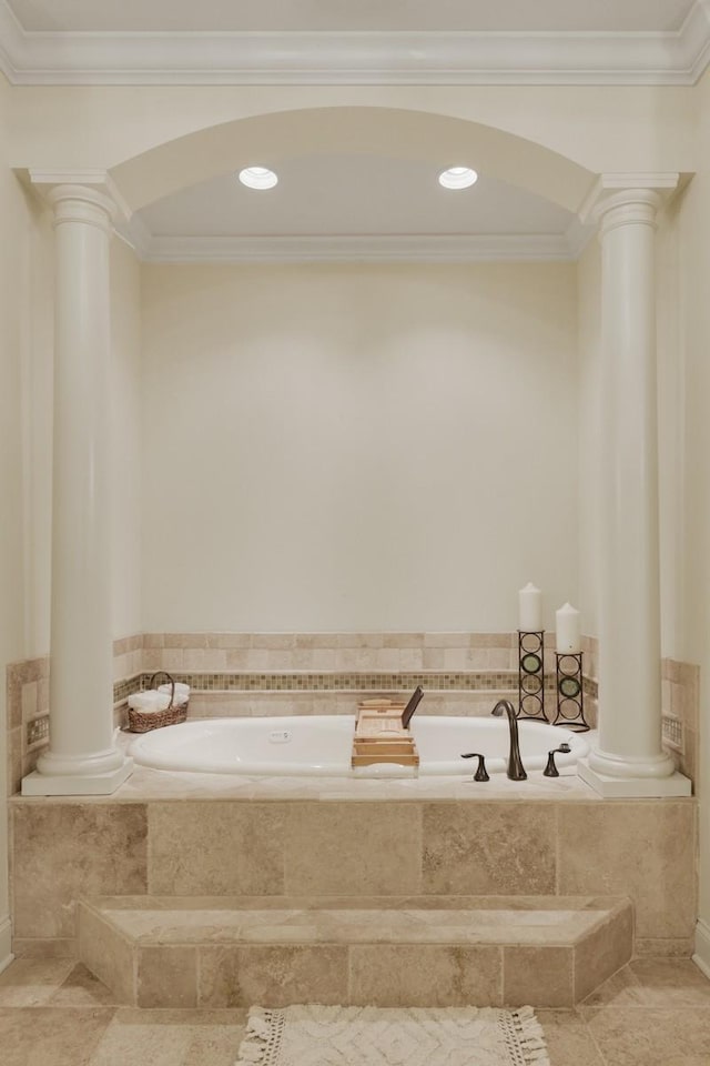 bathroom featuring ornate columns, crown molding, and tiled tub