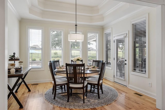 dining area featuring ornamental molding, a raised ceiling, visible vents, and light wood-style floors