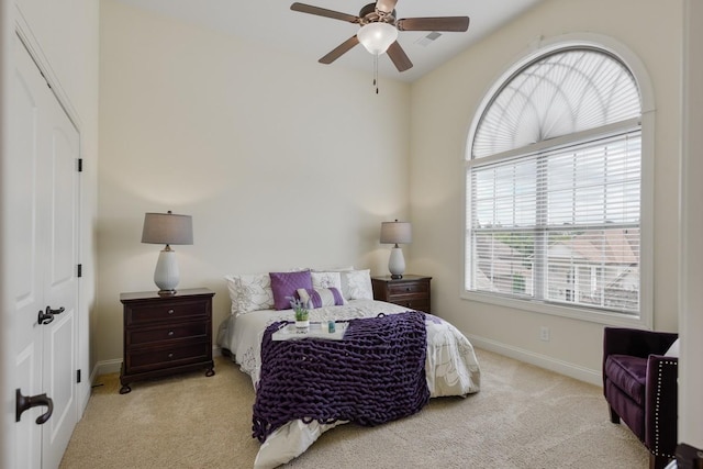 bedroom featuring light carpet, a ceiling fan, and baseboards