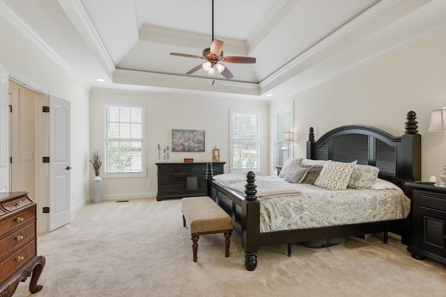 bedroom with baseboards, light colored carpet, ceiling fan, ornamental molding, and a tray ceiling