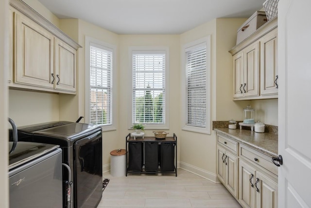 clothes washing area with cabinets and washing machine and clothes dryer