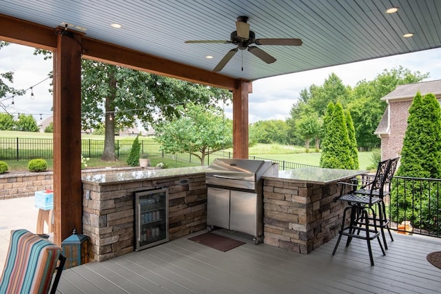 view of patio / terrace featuring area for grilling, a ceiling fan, fence, outdoor wet bar, and a wooden deck