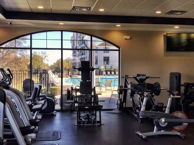 gym with visible vents, a paneled ceiling, and crown molding