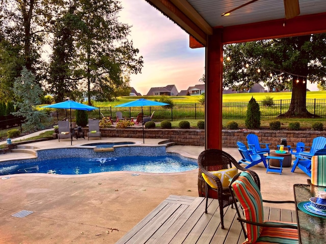 pool at dusk with an in ground hot tub, ceiling fan, and a patio