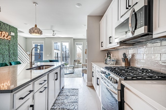 kitchen featuring appliances with stainless steel finishes, white cabinetry, sink, dark stone counters, and decorative backsplash