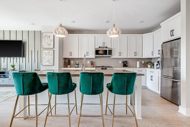 kitchen featuring stainless steel appliances, white cabinetry, sink, and pendant lighting