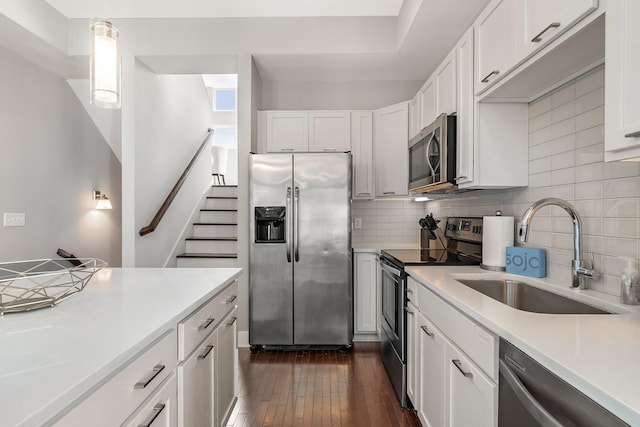 kitchen with dark wood-type flooring, sink, appliances with stainless steel finishes, pendant lighting, and white cabinets