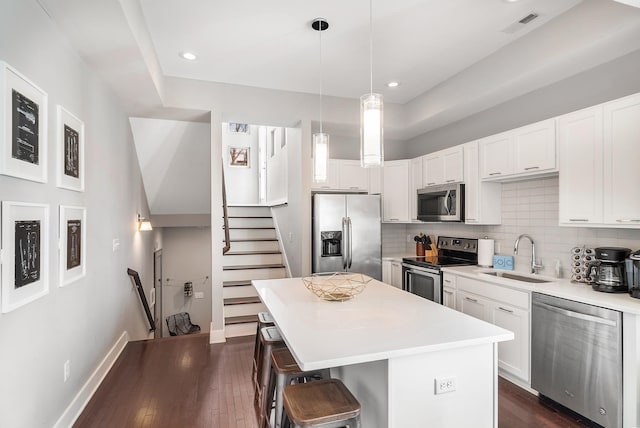 kitchen featuring sink, appliances with stainless steel finishes, white cabinetry, a kitchen island, and decorative light fixtures