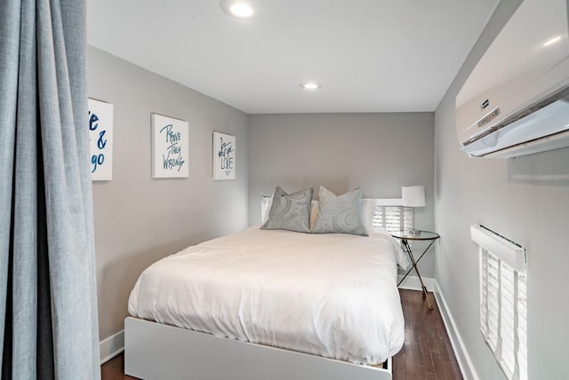 bedroom featuring dark hardwood / wood-style floors and a wall unit AC