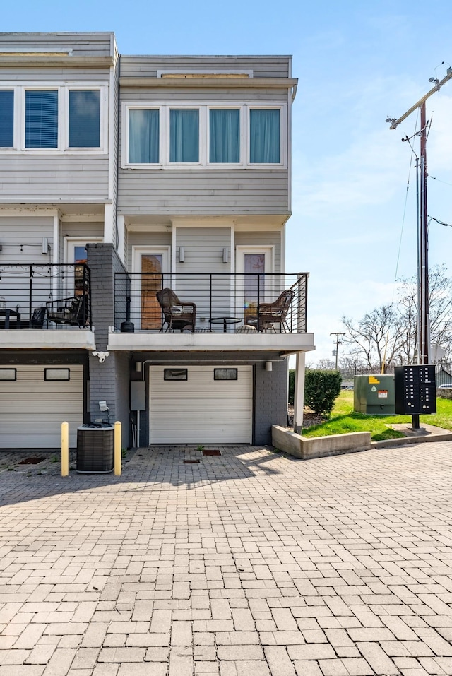 back of house featuring a garage, a balcony, and central air condition unit