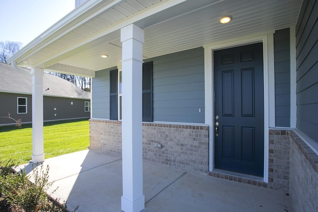 view of exterior entry with a porch and a yard