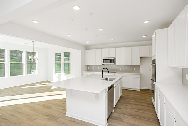 kitchen featuring sink, white cabinetry, light wood-type flooring, an island with sink, and stainless steel appliances