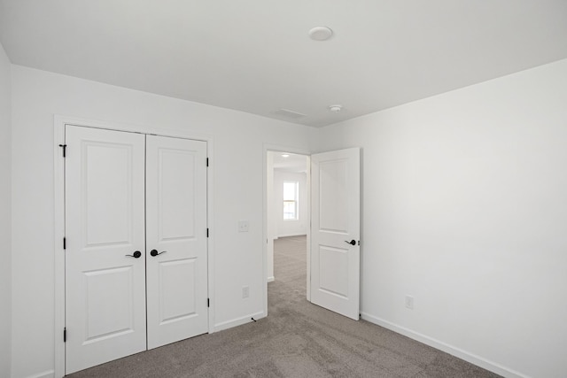 unfurnished bedroom featuring light colored carpet and a closet