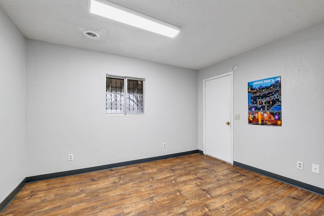 unfurnished room with dark wood-type flooring and a textured ceiling