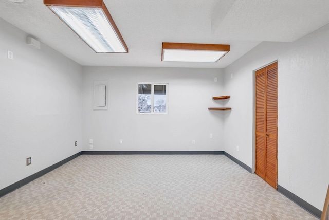 unfurnished room with a textured ceiling, light colored carpet, and electric panel