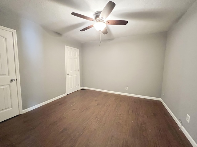 empty room featuring dark wood-type flooring and ceiling fan