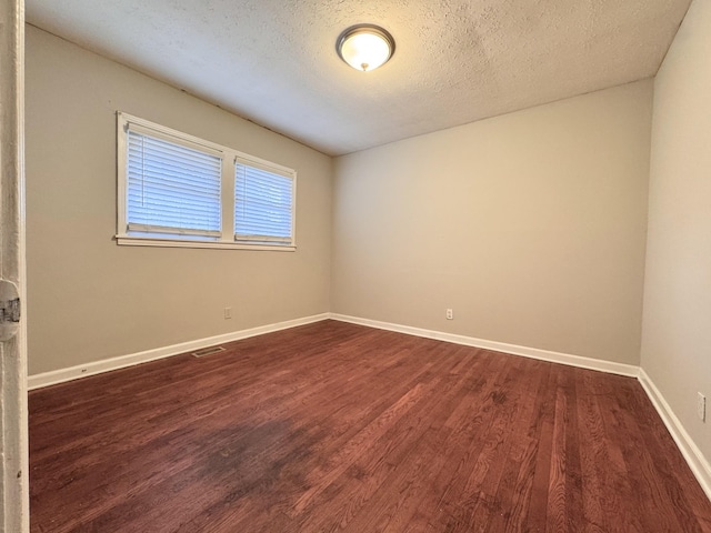 unfurnished room with dark wood-type flooring and a textured ceiling