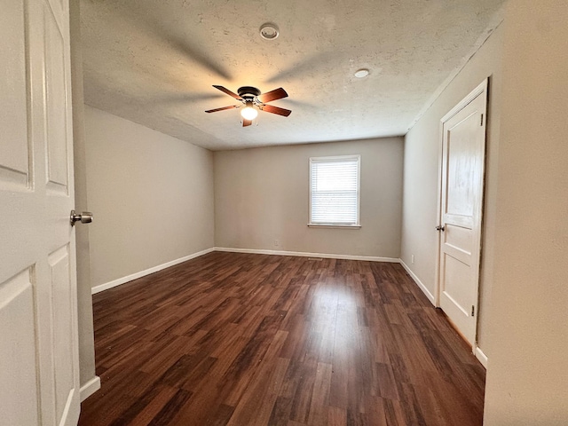 empty room with ceiling fan, a textured ceiling, and dark hardwood / wood-style flooring