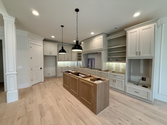 kitchen with a center island, light hardwood / wood-style floors, and decorative columns