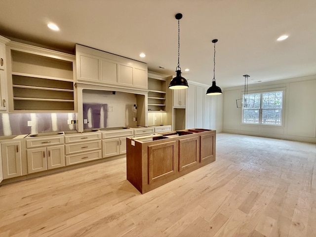 kitchen featuring pendant lighting, crown molding, light hardwood / wood-style flooring, and a center island