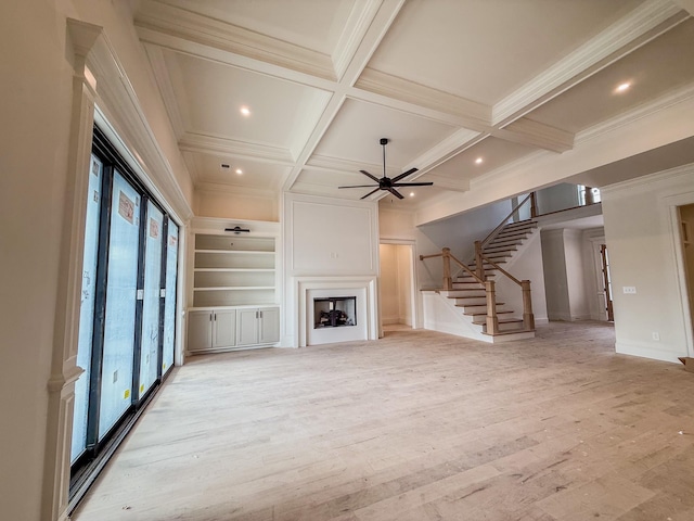 unfurnished living room with beam ceiling, crown molding, a large fireplace, coffered ceiling, and stairs