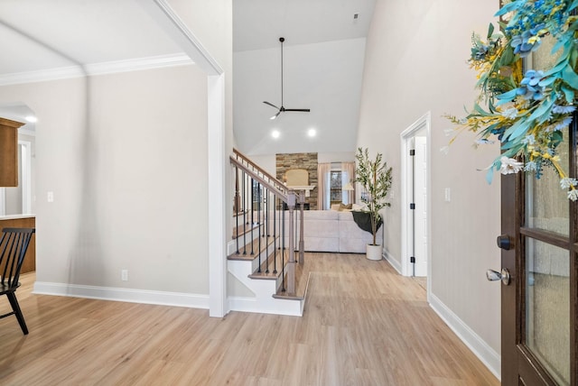 foyer featuring a high ceiling, ornamental molding, and light hardwood / wood-style flooring