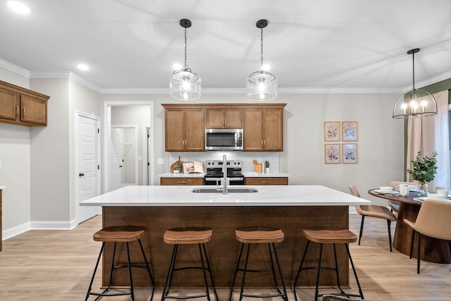 kitchen with sink, light hardwood / wood-style flooring, appliances with stainless steel finishes, pendant lighting, and backsplash