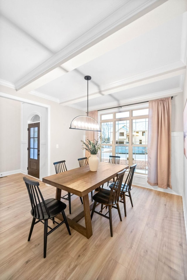 dining space with beamed ceiling, ornamental molding, a chandelier, and light hardwood / wood-style floors