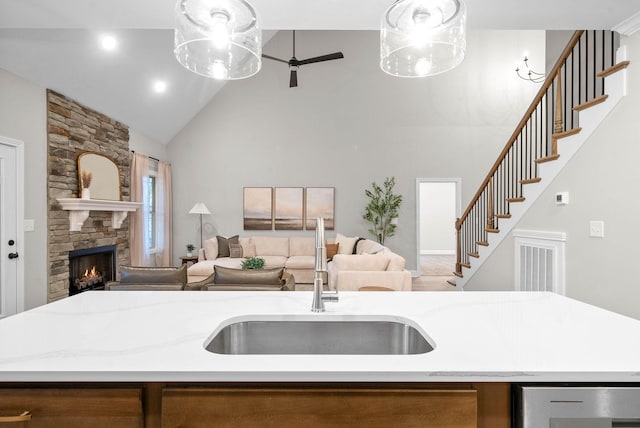 kitchen with sink, hanging light fixtures, high vaulted ceiling, and an island with sink