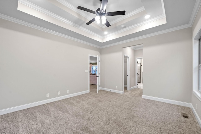 carpeted empty room featuring crown molding, a tray ceiling, and ceiling fan