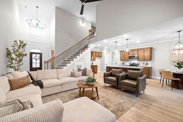 living room featuring crown molding, a chandelier, light hardwood / wood-style flooring, and a high ceiling