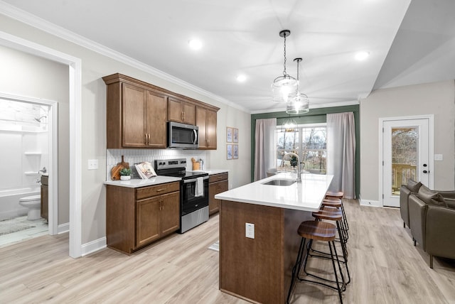 kitchen with sink, crown molding, a breakfast bar, appliances with stainless steel finishes, and an island with sink