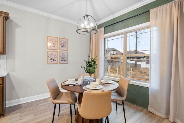 dining space with light hardwood / wood-style flooring, ornamental molding, and a chandelier