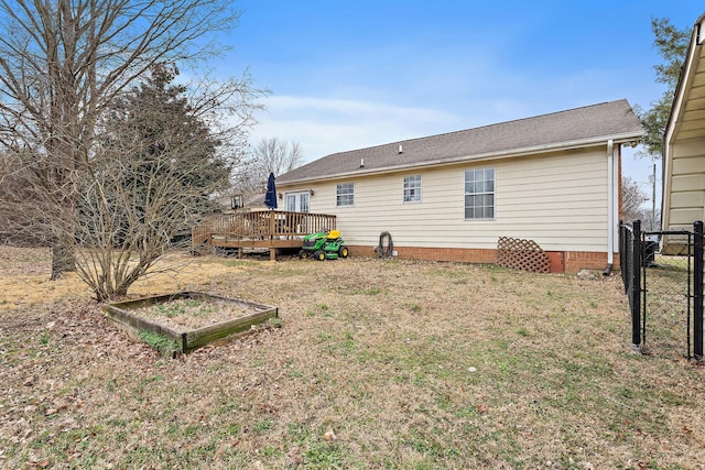 back of property featuring a wooden deck and a lawn