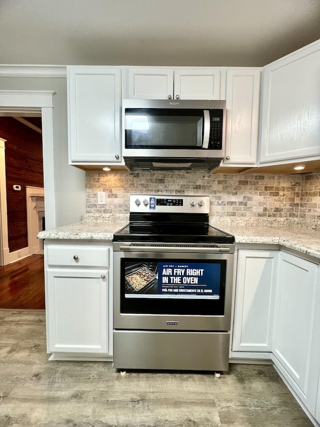 kitchen with white cabinetry, decorative backsplash, light hardwood / wood-style flooring, and stainless steel appliances