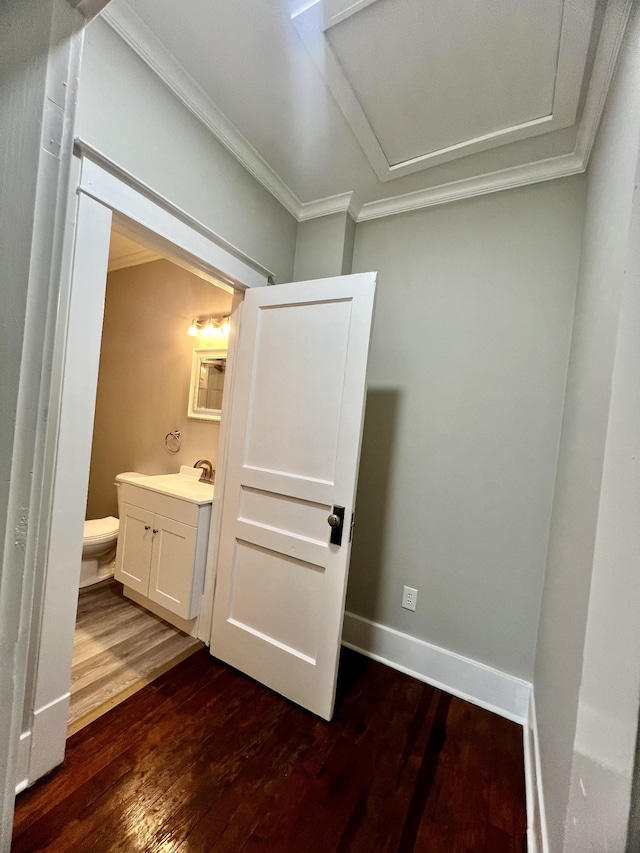 interior space with hardwood / wood-style flooring, ornamental molding, vanity, and toilet