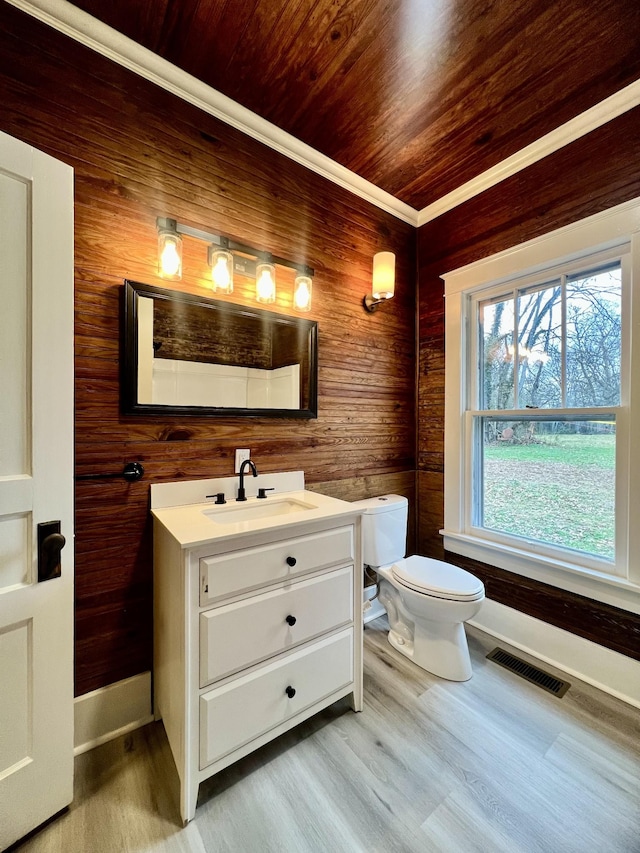 bathroom with hardwood / wood-style flooring, vanity, wooden walls, and toilet