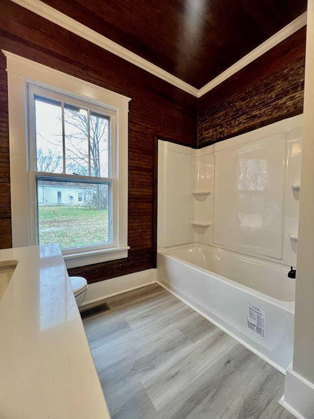 bathroom with tub / shower combination, hardwood / wood-style floors, and toilet