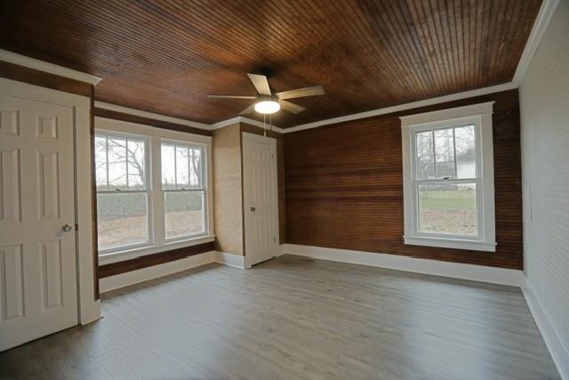 spare room with ceiling fan, ornamental molding, wooden ceiling, and light wood-type flooring