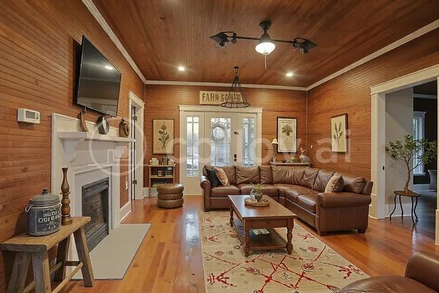 living room featuring french doors, ornamental molding, hardwood / wood-style flooring, and wooden ceiling