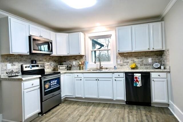 kitchen with sink, white cabinets, decorative backsplash, stainless steel appliances, and light wood-type flooring