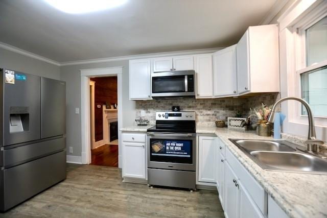 kitchen with sink, appliances with stainless steel finishes, backsplash, light hardwood / wood-style floors, and white cabinets