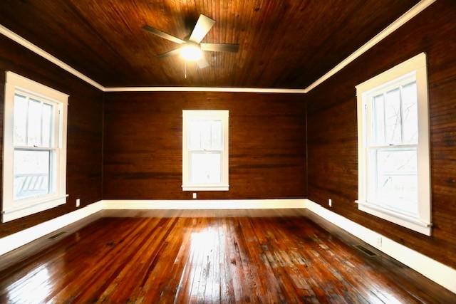 additional living space with dark wood-type flooring, wooden ceiling, ceiling fan, and plenty of natural light