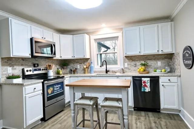 kitchen featuring appliances with stainless steel finishes, light hardwood / wood-style floors, sink, and white cabinets