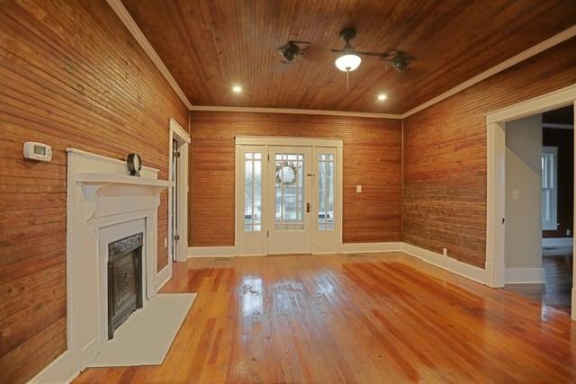 foyer entrance featuring hardwood / wood-style floors, wooden ceiling, ceiling fan, and wood walls